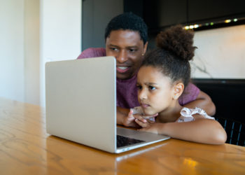 Father helping and supporting his daughter with online school while staying at home. New normal lifestyle concept.